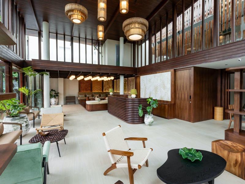 Modernes Hotel-Lobby mit offenen Holzwänden, Sitzbereichen und großen Hängelampen.