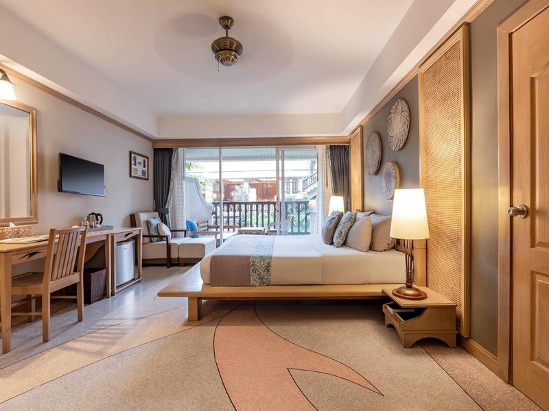 Gemütliches Schlafzimmer mit großem Bett, Holzmöbeln, Teppich und Balkon mit Tageslicht.