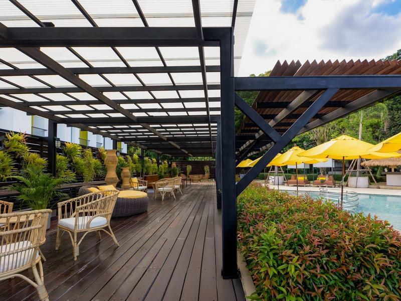 Outdoor-Bereich mit Pergola, Sitzgelegenheiten und Pool mit gelben Sonnenschirmen.