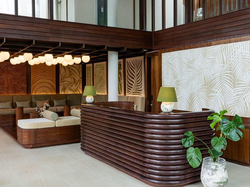 Modern eingerichtete Lobby mit Holzvertäfelungen, grünen Pflanzen und gemütlichen Sitzbereichen.