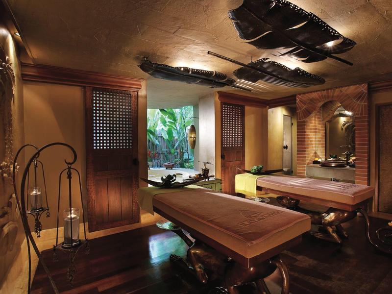 Luxuriöser Spa-Raum mit Massagetischen, gedämpftem Licht und warmen Holztönen.