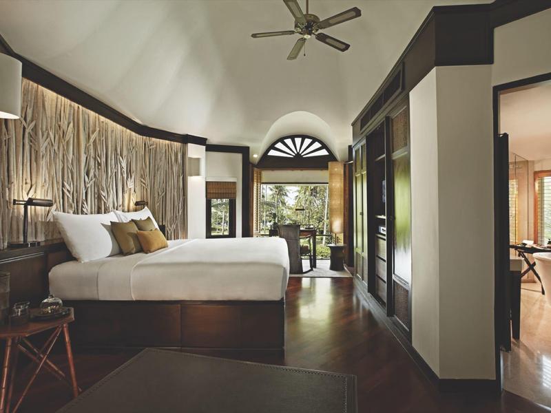 Geräumiges Schlafzimmer mit großem Bett, Holzdekoration, Ventilator und offenem Blick nach draußen.