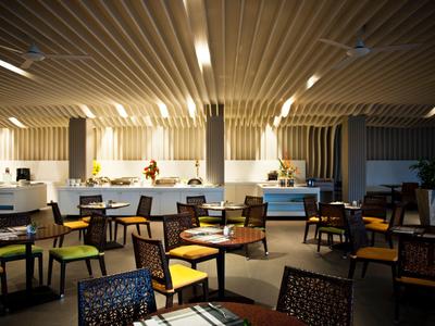 Eleganter Gastraum mit Holztischen, schwarzen Stühlen und warmem Deckenlicht in modernem Design.