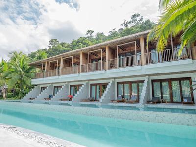 Modernes Hotel mit großen Glasfronten und Pool, umgeben von Palmen und grüner Natur.