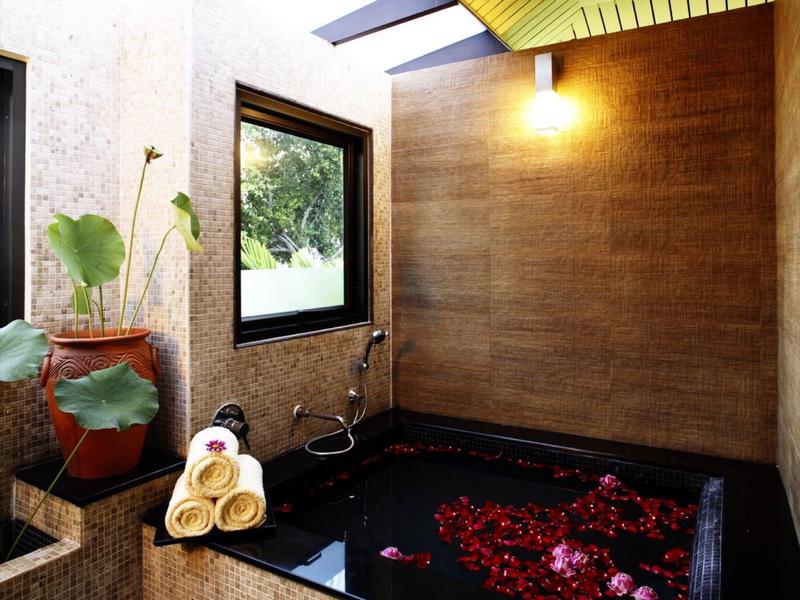 Modernes Bad mit schwarzer Badewanne, schrägem gelbem Dach und Pflanzen am Fenster.