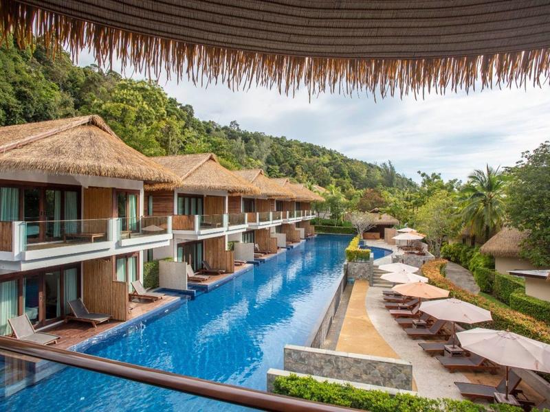 Luxuriöse Bungalows mit direktem Zugang zu einem langen Pool, umgeben von Grünflächen und Sonnenschirmen.