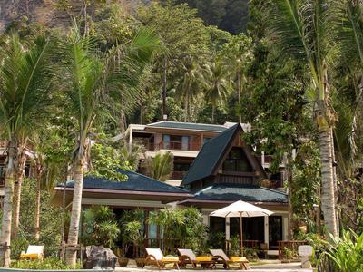 Moderner Bungalow mit Pool, umgeben von Palmen und hohen Felsen im Hintergrund.