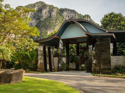 Vstup s tradiční střechou před horou v zeleném hotelovém areálu.