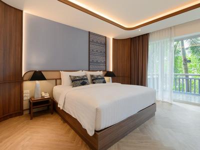 Moderní ložnice s velkou postelí, dřevěným nábytkem a balkonem s výhledem na zahradu.