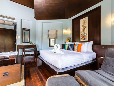 Moderně zařízený hotelový pokoj s manželskou postelí, dřevěnou podlahou a posezením.