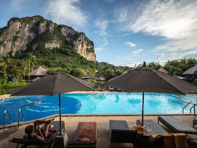 Grande piscine avec parasols et montagne en arrière-plan par une journée ensoleillée.