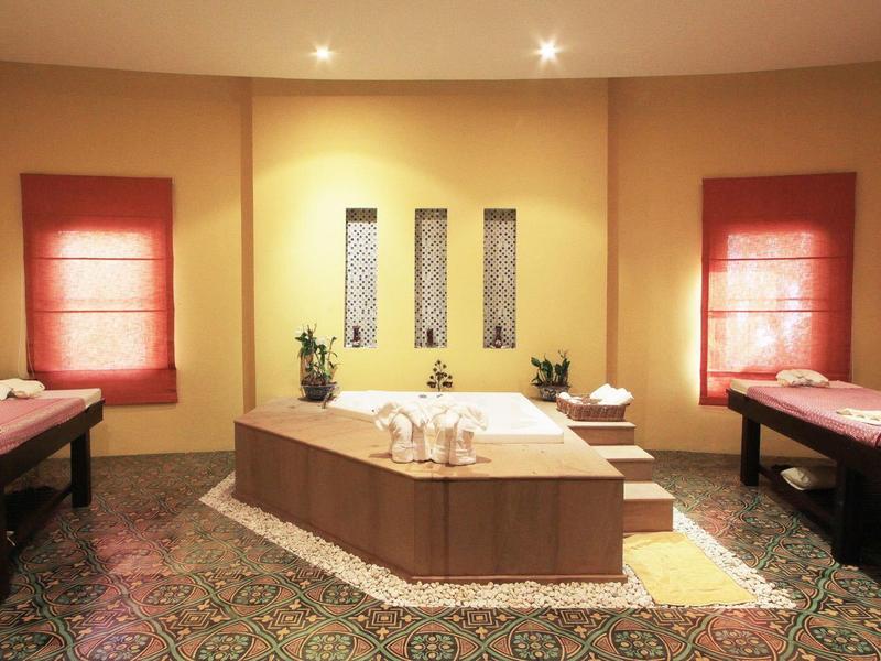 Pokojná wellness místnost se dvěma masážními lehátky a centrálním dřevěným stolem s ručníky.