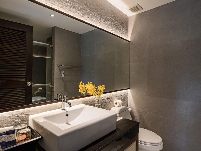 Moderní hotelová koupelna s velkým zrcadlem, umyvadlem a elegantním osvětlením.