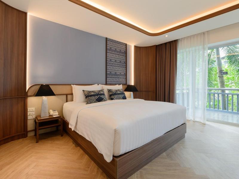 Moderní ložnice s velkou postelí, dřevěným nábytkem a balkonem s výhledem na zahradu.