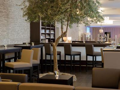 Modern eingerichteter Hotel-Loungebereich mit Stühlen, Tischen und einer Baumdekoration.