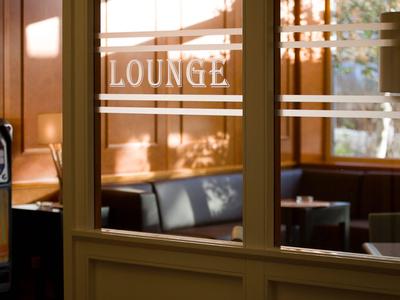 Gemütlicher Lounge-Bereich mit Ledersofas, Glastischen und warmem Holzinterieur.