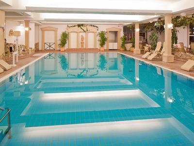 Innenpool mit Liegestühlen und sanfter Beleuchtung in einem Hotelbereich.