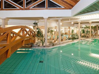 Gemütlicher Indoor-Pool mit Holzbrücke und begrünten Säulen in einem Hotel.