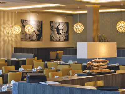 Modernes Restaurant mit stilvollen Lampen, gedeckten Tischen und dekorativen Kunstwerken an der Wand.