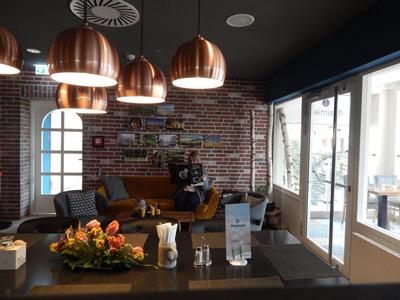 Gemütliche Hotellounge mit Backsteinwand, Ledersofa und Kupferlampen über einem Couchtisch.