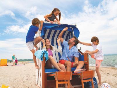 Family with two kids sitting in a beach chair by the sea on a sunny day.