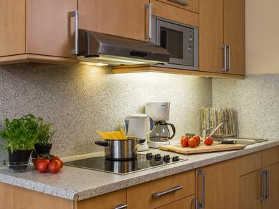 Moderne kitchenette met granieten aanrecht, kookplaat, magnetron en verse ingrediënten.