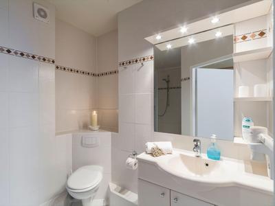 Helder verlichte hotelbadkamer met toilet, wastafel en grote spiegel.