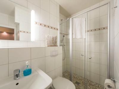 Compacte badkamer met douche, wastafel, toilet en moderne tegels.
