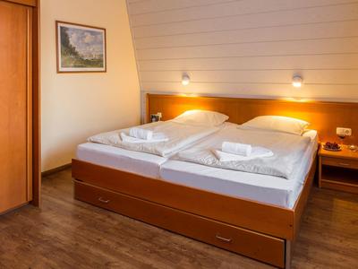 Gemütliches Schlafzimmer mit zwei Einzelbetten, Holzdekor, Nachttischen und warmem Licht.