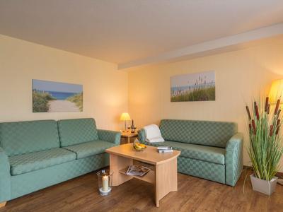 Gezellige hotelkamer met twee banken, houten tafel en moderne verlichting.