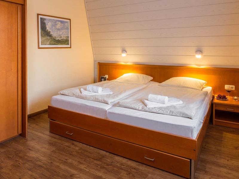 Gemütliches Schlafzimmer mit zwei Einzelbetten, Holzdekor, Nachttischen und warmem Licht.