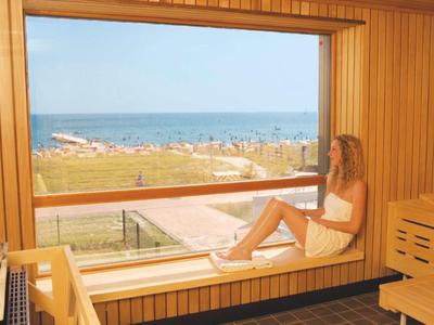 Zimmer mit großer Holzfensterbank mit Meerblick und einer Person in Handtuch.