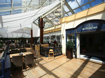 Ein überdachter Außenbereich eines Hotels mit Tischen, Stühlen und Sonnenschutz.