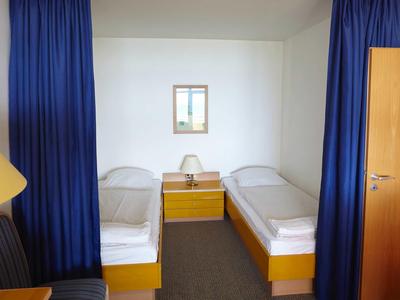 Zwei Einzelbetten im Hotelzimmer mit blauem Vorhang zwischen ihnen.