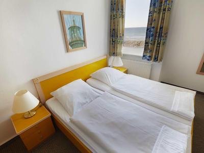 Ein einfach eingerichtetes Hotelzimmer mit zwei Einzelbetten, einem Nachttisch und einem Fenster mit Blick.