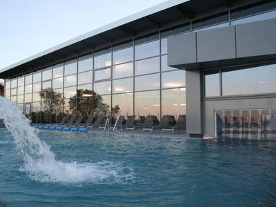 Moderner Hotelpool mit Wasserspielen und großen Glasfenstern am Gebäude.