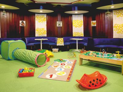 Kinderspielbereich mit buntem Spielzeug, Tunneln und Möbeln in einem Hotellobby-Raum.
