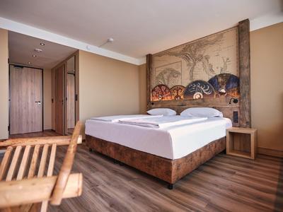 Schlafzimmer mit Doppelbett, Holzfußboden und asiatisch inspiriertem Wandbild im Hotel
