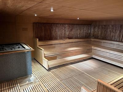 Holzsauna mit abgestuften Sitzbänken und gedämpftem Licht.