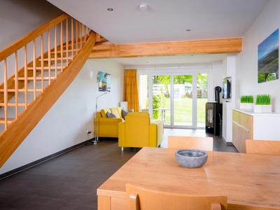 Helles Wohn- und Esszimmer mit Holzmöbeln, gelbem Sofa und Blick auf Garten