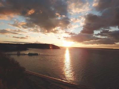 Sonnenuntergang über einem ruhigen See mit bewölktem Himmel und einer kleinen Anlegestelle.