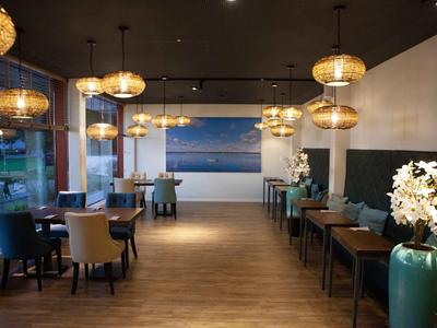 Elegantes Restaurant mit Holzboden, moderner Beleuchtung und stilvoller Einrichtung.