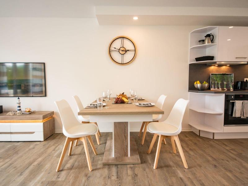 Modern dining area with white table and chairs in an open-plan kitchen.