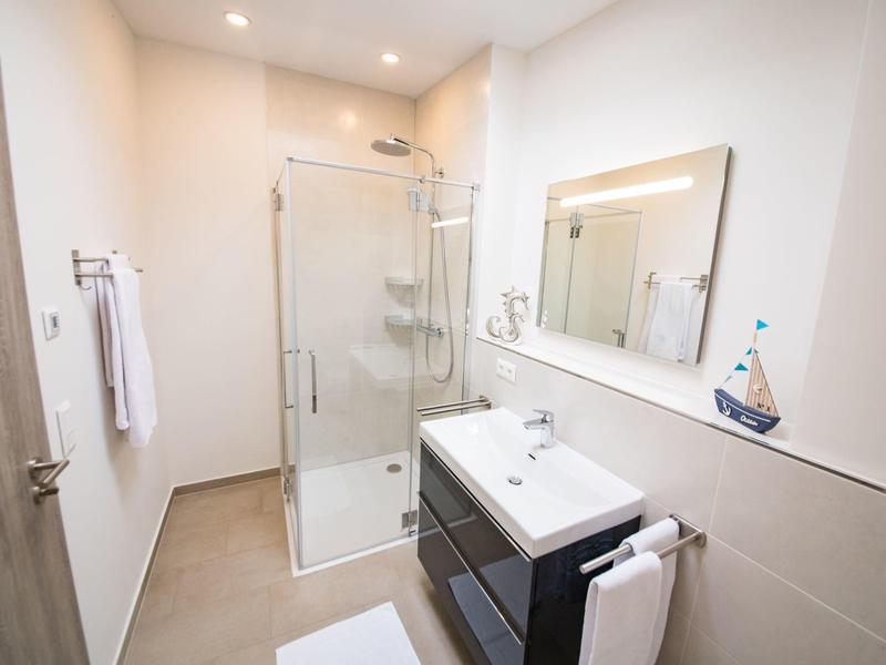 Modern bathroom with shower, sink, mirror, and bright walls in a hotel.