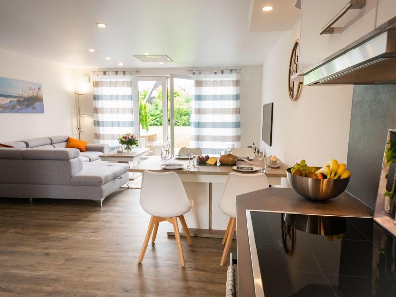 Modern living room with dining table and adjoining kitchenette in bright apartment.