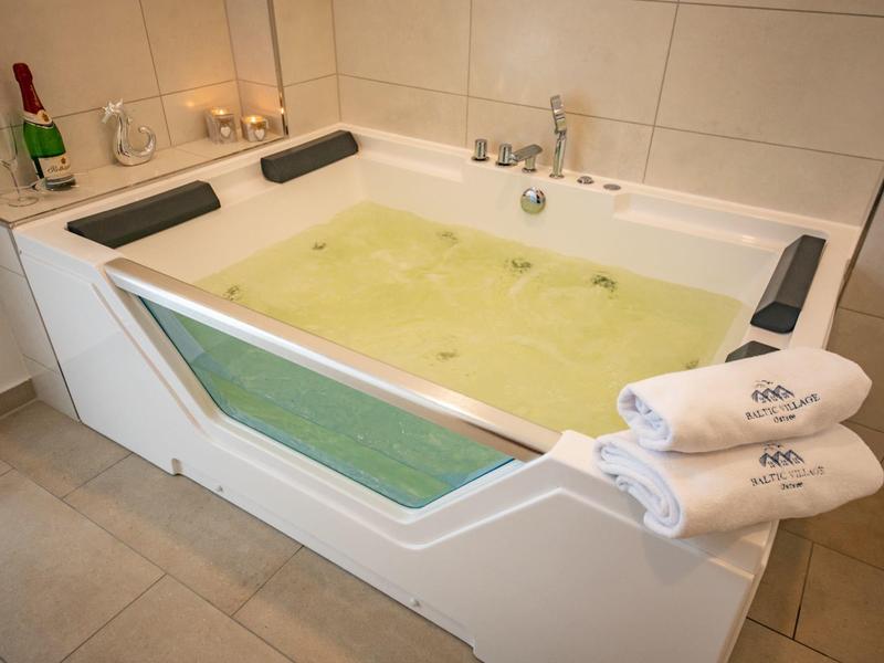 Whirlpool bathtub with green illuminated water, headrests, and towels nearby