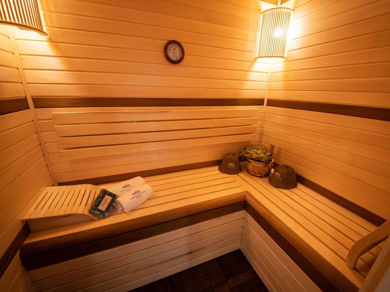 Cozy Finnish sauna with wooden benches and wall lighting.
