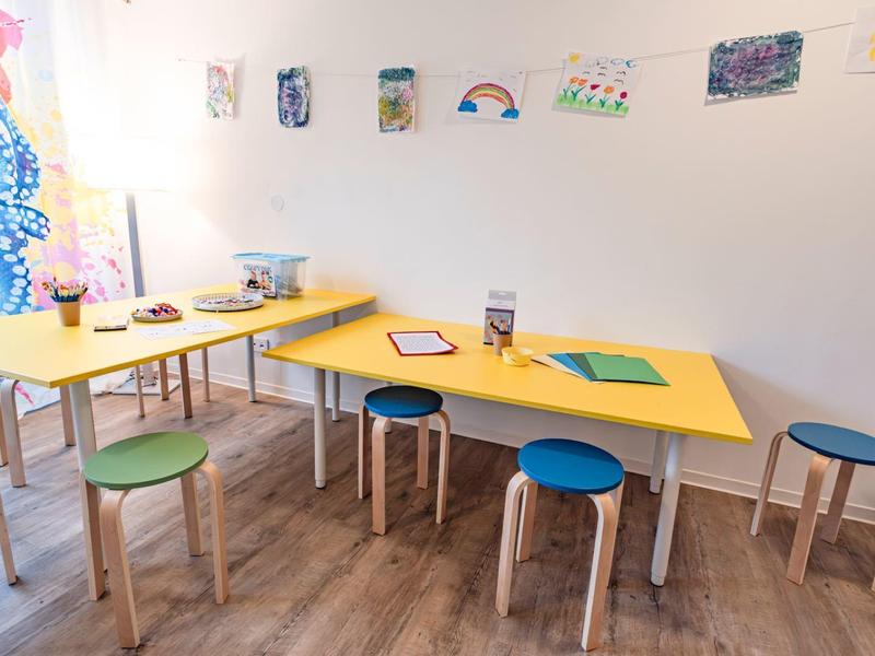 Colorful tables and stools in a bright, modern common room with wall decorations.