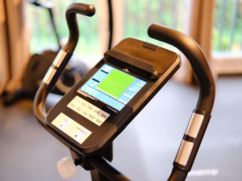 Exercise bike console with touchscreen and heart rate sensors on handlebars.