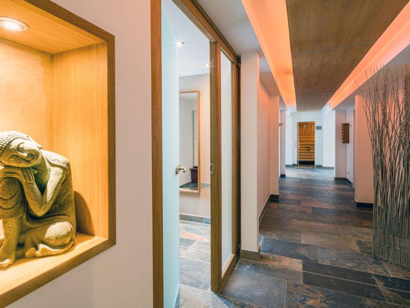 Hallway with stone floor, recessed niche with sculpture, and indirect lighting.